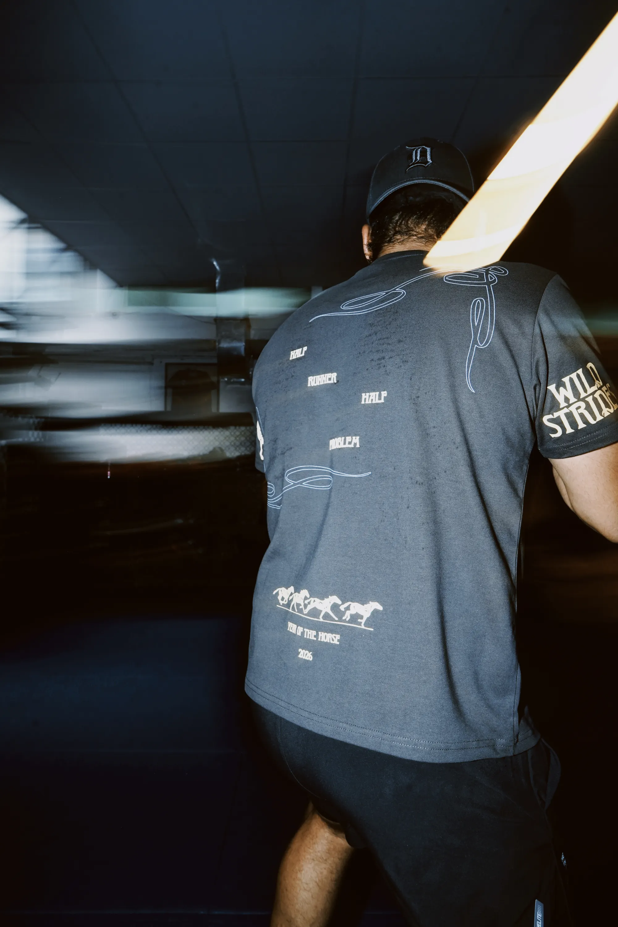 Wild Strides Tee in Ash, back print, worn at the Combat Lab