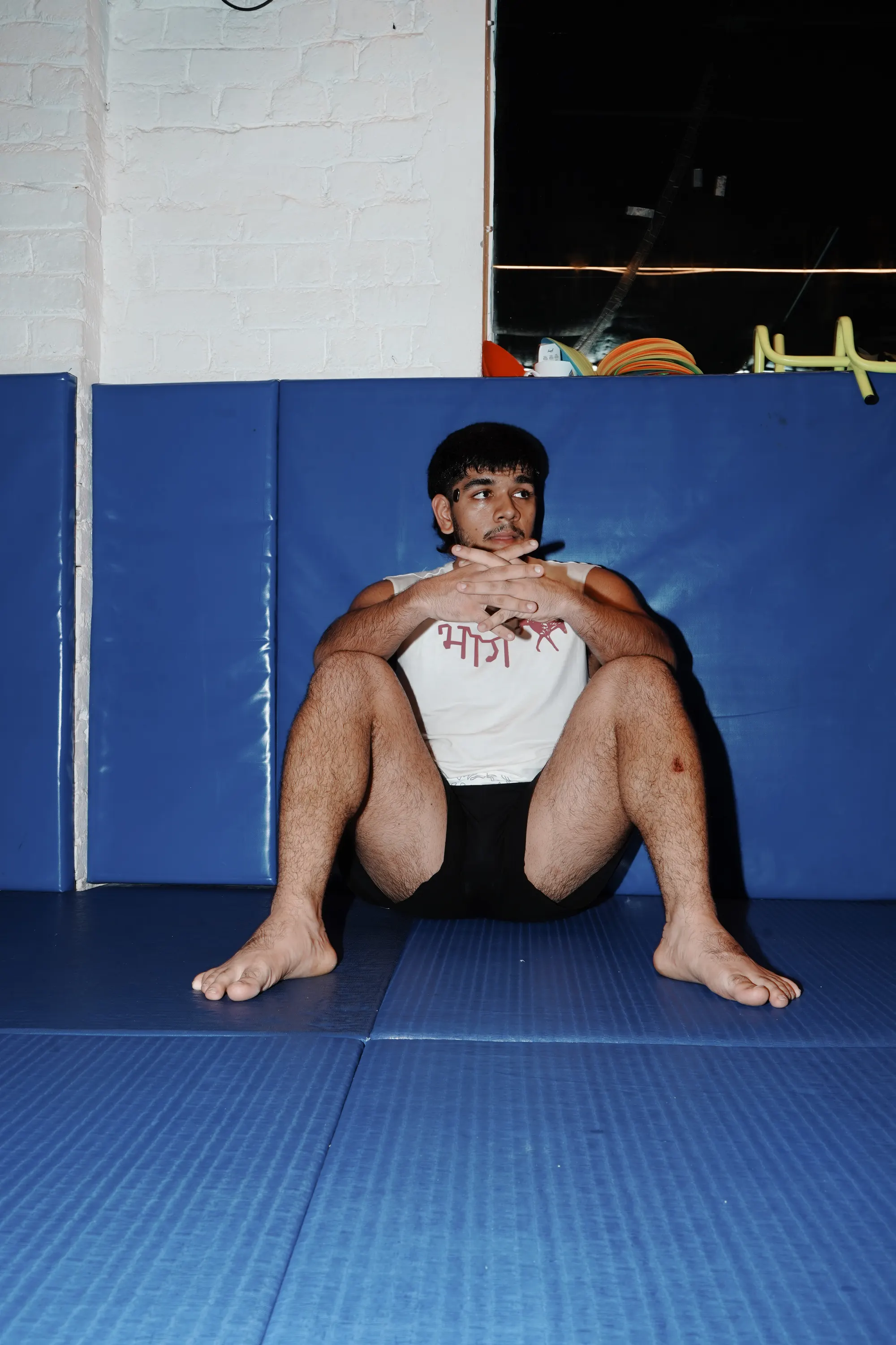 भाग Muscle Tank in Bone, worn loose, seated on the mats